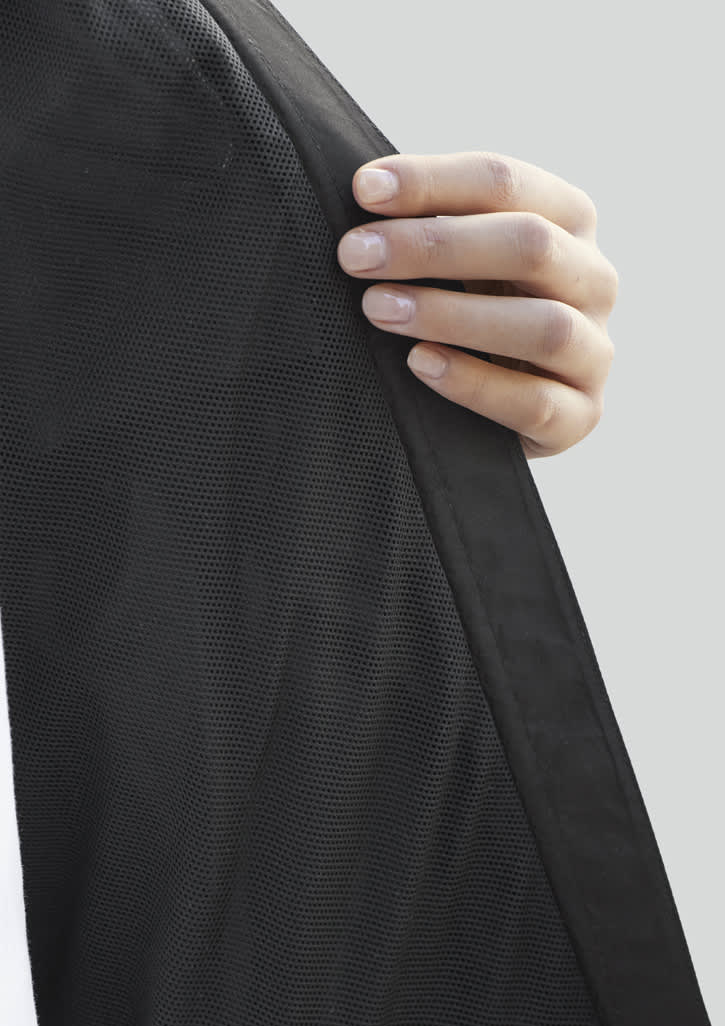 A hand holds the edge of a Women's Tempest Jacket, showcasing its black fabric texture and design.